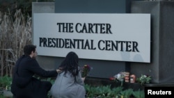 Seorang perempuan tampak menaruh bunga di depan kantor The Carter Presidential Center, menyusul kabar meninggalnya mantan Presiden AS Jimmy Carter di usia 100 tahun, di Atlanta, Georgia, pada 29 Desember 2024. (Foto: Reuters/Elijah Nouvelage)