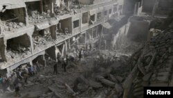 Warga memeriksa sebuah lokasi yang hancur setelah serangan udara yang dilancarkan oleh pasukan setia Presiden Bashar al-Assad di Douma, sebelah timur al-Ghouta, dekat Damaskus (24/9).