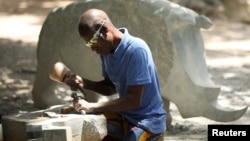 Zimbabwean sculptor Dominic Benhura works on a piece at his studio in Harare, Zimbabwe, March 2, 2020. (REUTERS/Philimon Bulawayo)
