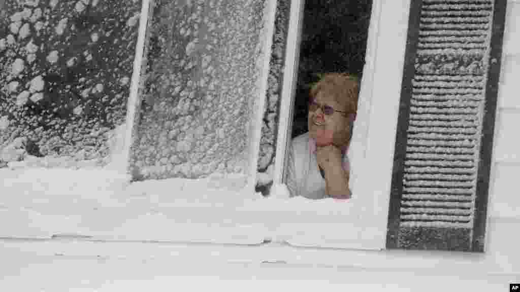 Rita Valente regarde, depuis la fenêtre, la neige tomber dans le quartier East Boston de Boston, dimanche 15 février, 2015. Une tempête a apporté un nouveau cycle de vent fouettée neige en Nouvelle-Angleterre, le dimanche.