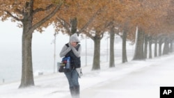 Seorang perempuan berjuang melawan angin kencang dan salju saat berjalan dari Adler Planetarium di Chicago ke Chicago Aquarium, di Chicago, Senin, 11 November 2019. (Foto: AP)