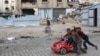 Palestinian children play in a red toy car near their displacement camp in Beit Lahia in the northern Gaza Strip, ahead of the iftar fast-breaking meal during the Muslim holy month of Ramadan on March 9, 2025.