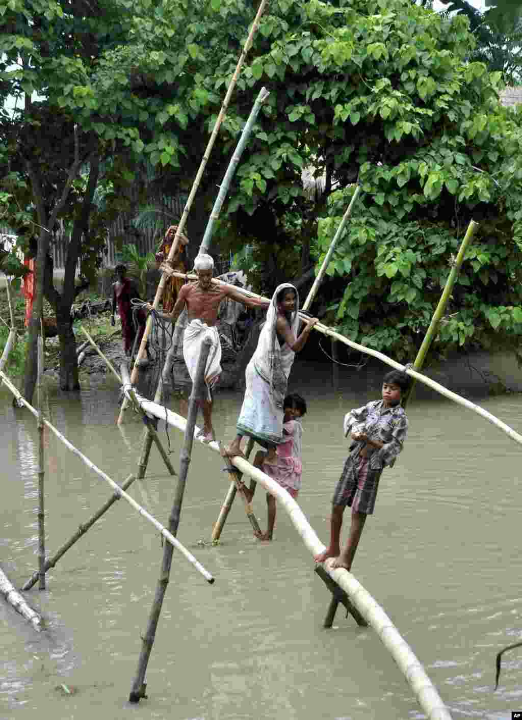 Indian villagers use a bamboo structure to move across a flooded village in the northeastern Assam state, India, Aug. 18, 2014.