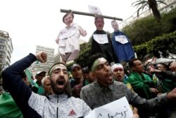 FILE - People carry a mock hangman with faces of businessman Ali Haddad, former Prime Minister Ahmed Ouyahia, and Said Bouteflika, brother of the former president, during a protest against the political structure, in Algiers, Algeria, April 5, 2019.