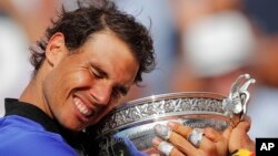 Petenis Spanyol Rafael Nadal memegang piala Perancis Terbuka setelah mengalahkan Stan Wawrinka dalam tiga set: 6-2, 6-3, 6-1 di Paris, Minggu (11/6). 