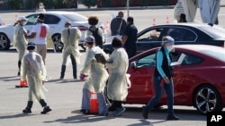 Health officials use wireless devices to register people with vaccine appointments at a mass COVID-19 vaccination site outside The Forum in Inglewood, Calif., Tuesday, Jan. 19, 2021.