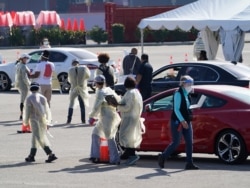Health officials use wireless devices to register people with vaccine appointments at a mass COVID-19 vaccination site outside The Forum in Inglewood, Calif., Jan. 19, 2021.