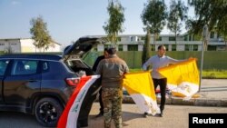 Christians volunteers hold Iraqi and Vatican flags as they decorate streets ahead of the planned visit of Pope Francis, in Qaraqosh, Iraq, Feb. 22, 2021. 