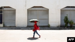 Seorang perempuan menggunakan payung untuk berlindung dari terik matahari saat cuaca panas di Manila pada 28 April 2024. (Foto: AFP)