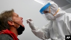 Seorang petugas tes Covid-19 maskapai penerbangan Lufthansa sedang melakukan uji usap di bandara Munich, Jerman, 12 November 2020. 