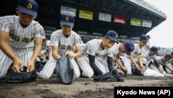 FILE - Akashi Commercial High School baseball players collect dirt of the grounds after being defeated by Riseisha High School during a semifinal game at the National High School Baseball Championship at Koshien Stadium in Nishinomiya on Aug. 20, 2019. (Kyodo News via AP)