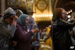 In this photo taken on Friday, May 26, 2017, Russian Orthodox believers cross themselves as they line up to kiss the relics of Saint Nicholas in the Christ the Savior Cathedral in Moscow, Russia.