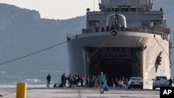 Migrants wait outside a military vessel after their disembarkation at the port of Elefsina, near Athens, Nov. 2, 2019