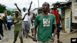 Demonstrators, some carrying machetes and stones, shout as police dismantle a barricade in the Kanyosha district of Bujumbura, Burundi, May 6, 2015. 