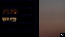 FILE - A passenger plane flies over Beirut, Lebanon, a capital in darkness because of a power outage, March 29, 2021.