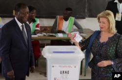 FILE - Ivory Coast's President Alassane Ouattara, left, and his wife, Dominique Ouattara, cast their ballots during the Ivory Coast referendum in Abidjan, Ivory Coast, Oct. 30, 2016.
