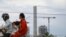 A family travels on a motorbike passing high rises under construction in Preah Sihanouk province, on October 5, 2021. (Sun Narin/VOA Khmer)