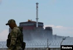 Seorang prajurit dengan bendera Rusia di seragamnya berjaga di dekat PLTN Zaporizhzhia di wilayah Zaporizhzhia, Ukraina, 4 Agustus 2022. (Foto: REUTERS/ Alexander Ermochenko)