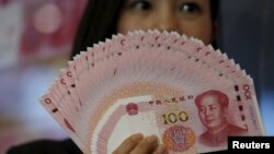 Seorang karyawan menunjukkan uang kertas Yuan di Bank of China Tower, Hong Kong, China, 12 November 2015. 