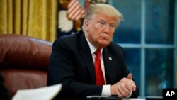 FILE - President Donald Trump listens to a question during an interview in the Oval Office of the White House, in Washington, Oct. 16, 2018.