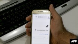 FILE - A man holds a smartphone connected to a Wifi network without internet access, at an office in the Iranian capital Tehran, Nov. 17, 2019.