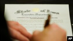 Seorang anggota Electoral College menandatangani Sertifikasi Pemungutan Suara Elektor untuk Negara Bagian Iowa, Senin, 14 Desember 2020. (AP Photo/Charlie Neibergall)