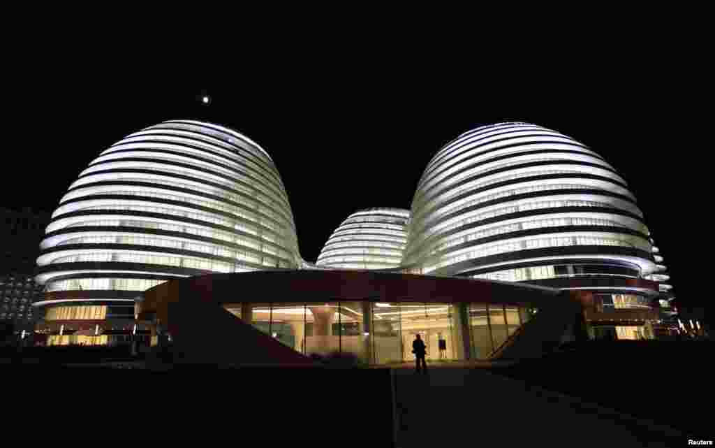 FILE - A visitor walks at the newly opened Galaxy Soho building, designed by Iraqi-British architect Zaha Hadid, in Beijing, China, Oct. 27, 2012.
