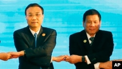 In this Sept. 7, 2016, photo, Chinese Premier Li Keqiang (L) and Philippine President Rodrigo Duterte link arms during the ASEAN Plus Three summit in Vientiane, Laos. After lashing out at longtime ally America, Duterte is making a state visit to Ch