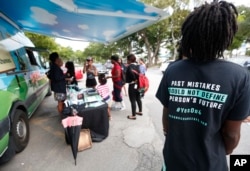 People gather around the Ben & Jerry's "Yes on 4" truck as they learn about Amendment 4 and eat free ice cream at Charles Hadley Park in Miami, Oct. 22, 2018.