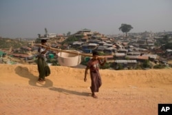 Rohingya refugees carry a hume pipe in Balukhali refugee camp near Cox's Bazar, in Bangladesh, Nov. 17, 2018.