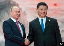 Chinese President Xi Jinping, right, and Russian President Vladimir Putin pose for a photo at the Shanghai Cooperation Organization (SCO) Summit in Qingdao in eastern China's Shandong Province, June 10, 2018.