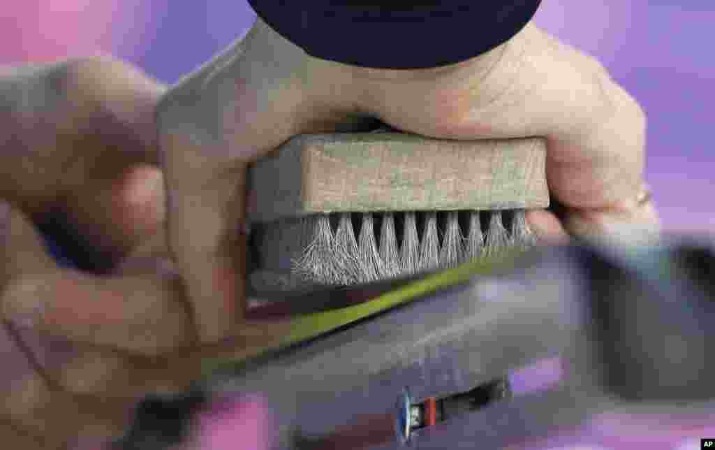 A waxing technician brushes a ski during the cross-country sprint competitions,&nbsp;Krasnaya Polyana, Feb. 11, 2014.