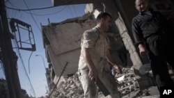Syrian men salvage belongings from a destroyed buildings in the Bustan al-Qasr neighborhood of Aleppo, Syria, September 21, 2012.
