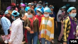 កម្មកររោងចក្រកាត់ដេរប្រភឹសឹស ខេមបូឌា ហ្គាមេន អិលធីឌី ក្នុងខេត្តកណ្តាល ចាប់ផ្តើមចេញពីរោងចក្រដើម្បីទទួលទានបាយថ្ងៃត្រង់ ដោយមានពាក់ម៉ាសគ្រប់គ្នា នៅថ្ងៃទី២០ ខែមីនា ឆ្នាំ២០២០។ (កាន់ វិច្ឆិកា/VOA Khmer)