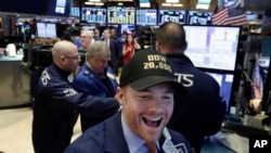 Pakar saham Frank Masiello mengenakan topi Dow Jones 20.000 saat bekerja di lantai Bursa Saham New York (NYSE), Rabu (25/1). Untuk pertama kalinya, indeks Dow Jones mencapai rekor tertinggi dengan pencapaian di atas 20.000. 