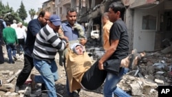 Para warga di Reyhanli dekat perbatasan Turki dengan Suriah mengangkat perempuan korban ledakan bom mobil, Sabtu (11/5). (AP/Anadolu Agency, Lale Koklu)