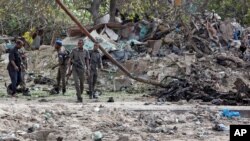 Somali soldiers attend the scene where a suicide car bomber detonated near the gates of the motor vehicle imports duty authority headquarters near the port in Mogadishu, Somalia, July 4, 2020. 
