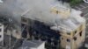 An aerial view shows firefighters battling fires at the site where a man started a fire after spraying a liquid at a three-story studio of Kyoto Animation Co. in Kyoto, western Japan, in this photo taken by Kyodo