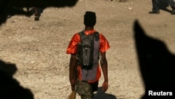 Seorang anggota geng berjalan setelah bentrok antara pasukan perdamaian PBB dan anggota geng di Port-au-Prince, Haiti, 22 Desember 2006. 