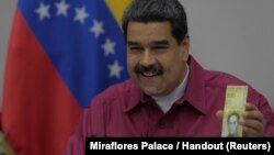 Venezuela's President Nicolas Maduro holds a 100,000 bolivar note while speaking with ministers in Caracas, Nov. 1, 2017. 