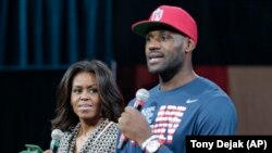 First lady Michelle Obama looks at Cleveland Cavaliers' basketball player LeBron James as he speaks at The University of Akron