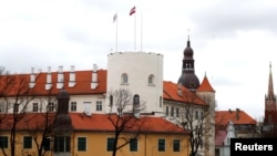 Latvian flag and presidential standard flutter over the Riga Castle, in Riga, Latvia, April 9, 2019.