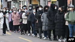 ពលរដ្ឋនៅទីក្រុងថេហ្គូ (Daegu) តម្រង់ជួរទិញម៉ាស់នៅហាងលក់ទំនិញមួយកន្លែងក្នុងតំបន់ពាណិជ្ជកម្ម Dongseongro នៅទីក្រុងថេហ្គូ កូរ៉េខាងត្បូង ថ្ងៃទី២៧ ខែកុម្ភៈ ឆ្នាំ២០២០។ 