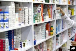 FILE - In this Nov. 5, 2018 file photo, a drugstore employee reaches for medicine from shelf in downtown Tehran, Iran. According to a study published in the British journal Lancet on Thursday, Aug. 22, 2019, researchers say a cheap daily pill that combine