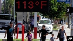 FILE - Pedestrians walk past a digital thermometer reading 113 degrees Fahrenheit (45 degrees Celsius) in the Canoga Park section of Los Angeles, Aug. 15, 2015. "The average surface air temperature for the year ending September 2016 is by far the highest since 1900," according to U.S. government data.