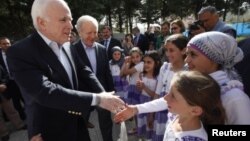 Les sénateurs McCain (à g.) et Lieberman saluent des enfants dans un camp de réfugiés près de la frontière turco-syrienne, le 10 avril 2012.