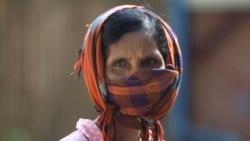 ស្ត្រីម្នាក់ប្រើក្រមាធ្វើជាម៉ាស់ការពារ ខណៈបុគ្គលិកប្រចាំអង្គការមូលនិធិកុមារកម្ពុជា (CCF) កំពុងបាញ់ថ្នាំសម្លាប់មេរោគដើម្បីជួយទប់ស្កាត់ការឆ្លងរាលដាលនៃវីរុសកូរ៉ូណាប្រភេទថ្មី នៅតំបន់ស្ទឹងមានជ័យ ជាយរាជធានីភ្នំពេញ ថ្ងៃទី២៤ ខែមីនា ឆ្នាំ២០២០។ 