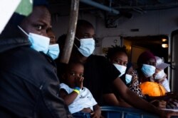 FILE - Migrants wait on board the German charity Sea-Watch 4 rescue ship before being transferred to GNV Allegra, where they will be in quarantine as part of anti-coronavirus measures, at sea near the Sicilian city of Palermo, Italy, Sept. 2, 2020.