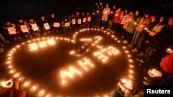 FILE - Participants of a vigil light candles during a tribute to passengers of missing Malaysia Airlines flight MH370, in Yangzhou, Jiangsu province, March 13, 2014.