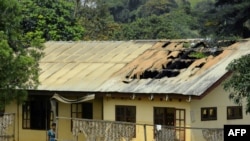 FILE - A woman stands outside a damaged school dormitory after it was set on fire in Bafut, in the northwest English-speaking region of Cameroon, Nov. 15, 2017. The military says it is helping clean up towns in efforts to implement new peace resolutions.